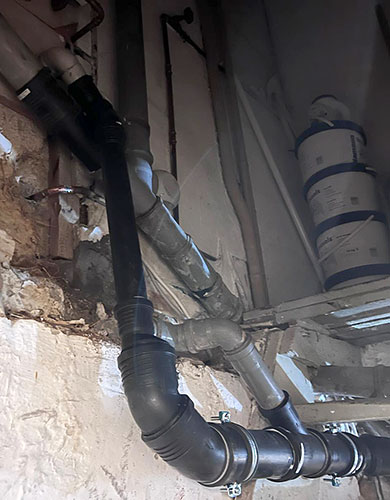 Komplette Rohrleitung für Fettabscheider Verschiedene Abwasserrohre für den Betrieb des Fettabscheiders verlaufen entlang einer Kellermauer