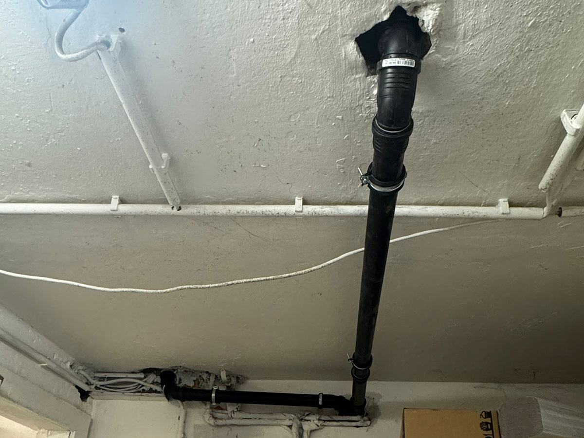 Zwei schwarze Rohrleitungen für den Fettabscheider die durch die Decke nach oben führen